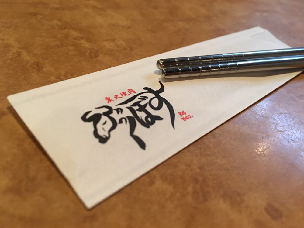 Photo of yakiniku restaurant logo and metal chopsticks.